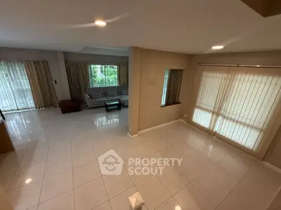 Spacious living room with large windows and tiled flooring, perfect for family gatherings.