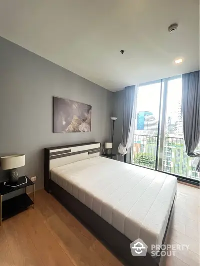 Modern bedroom with large window and city view, featuring stylish decor and natural light.