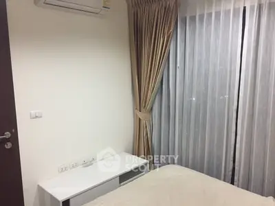 Cozy bedroom with modern decor and large window with elegant curtains.