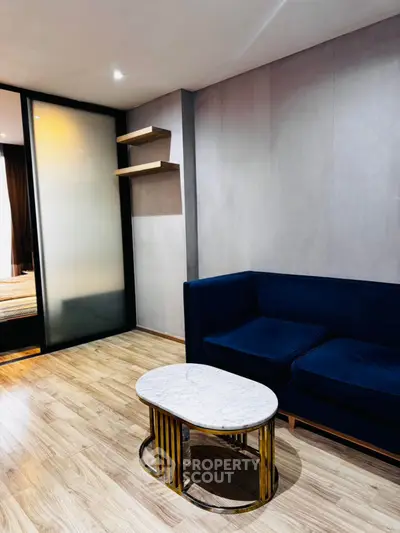 Modern living room with elegant blue sofa and marble coffee table on wooden flooring.