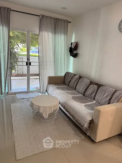Cozy living room with modern sofa and natural light from large window, perfect for relaxation.