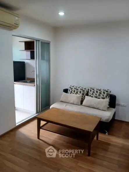 Cozy living room with wooden flooring and compact kitchen view