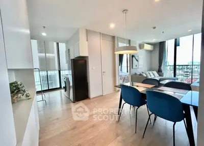 Modern open-plan living and dining area with sleek furnishings and large windows.