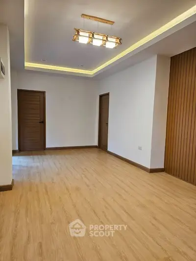 Spacious modern living room with wooden flooring and elegant lighting.