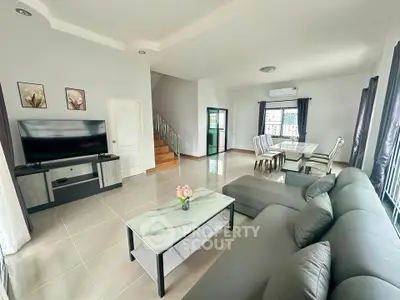 Spacious modern living room with elegant decor and dining area, featuring a large TV and comfortable seating.