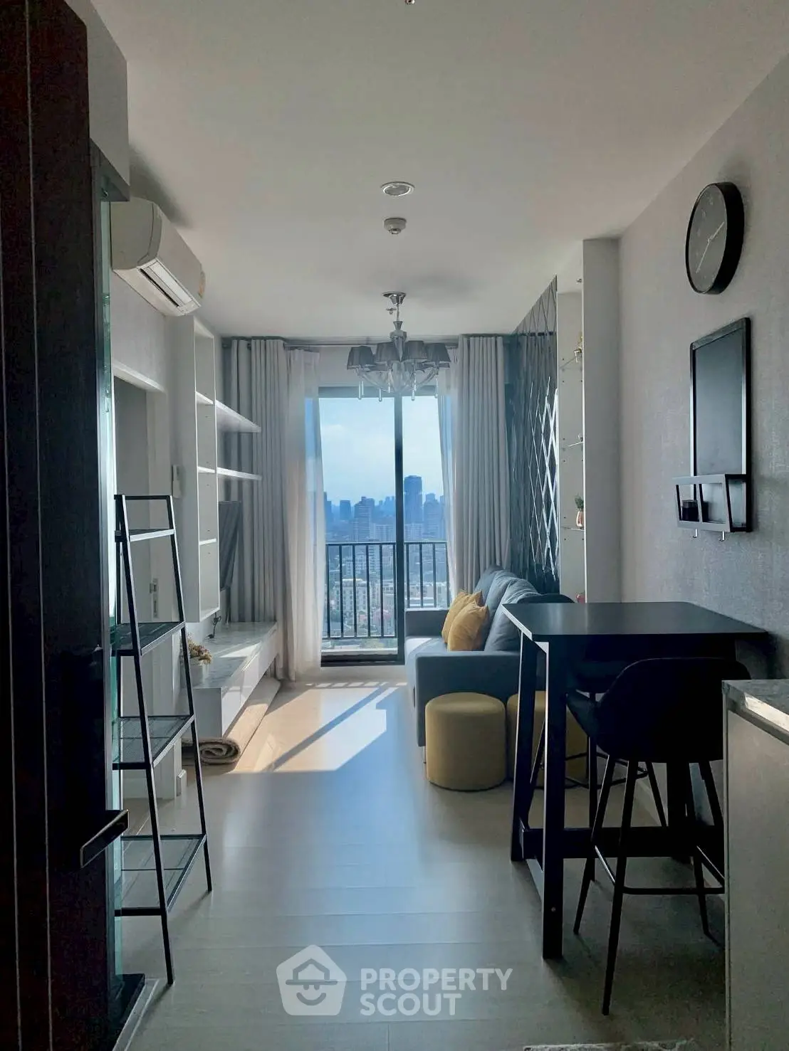 Modern living room with city view, stylish decor, and balcony access in a high-rise apartment.
