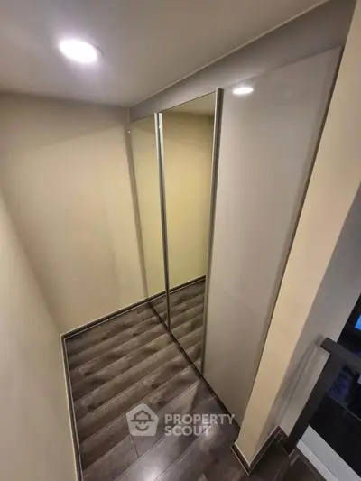 Modern hallway with sleek mirrored closet doors and elegant wood flooring