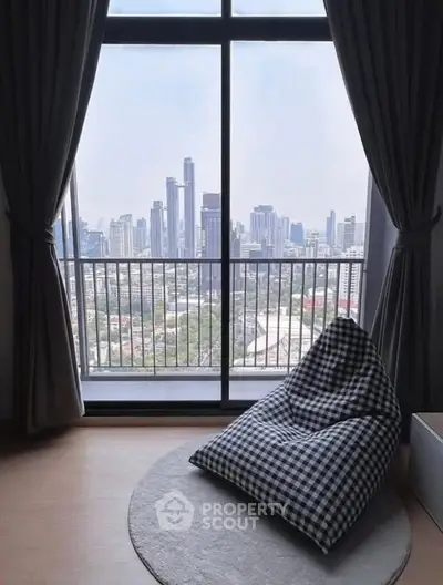 Stunning city view from modern apartment with cozy seating area.
