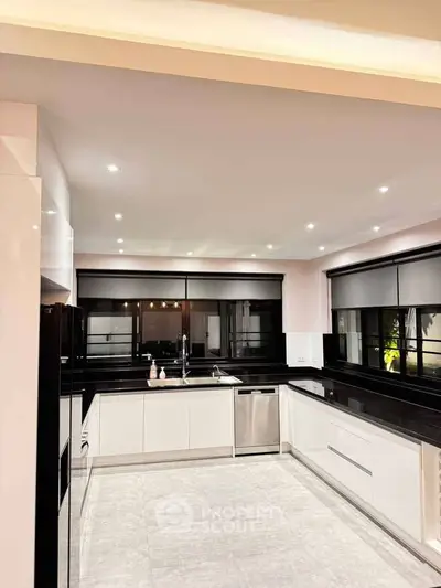 Modern kitchen with sleek black countertops and stainless steel appliances in a spacious layout.