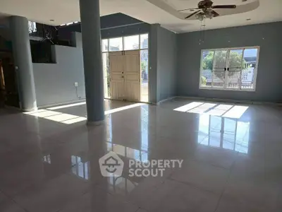 Spacious living room with large windows and ceiling fan, perfect for family gatherings.