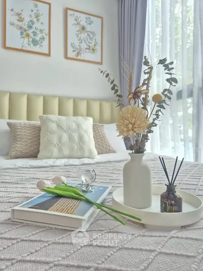 Elegant bedroom with cozy decor, featuring a stylish bed, decorative pillows, and a chic vase arrangement.