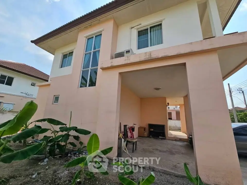 Charming two-story house with spacious carport and lush garden area, perfect for family living.