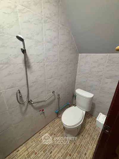 Compact bathroom with shower and toilet in tiled space