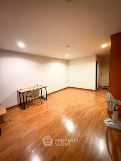 Spacious room with wooden flooring and minimalist furniture, ideal for versatile use.