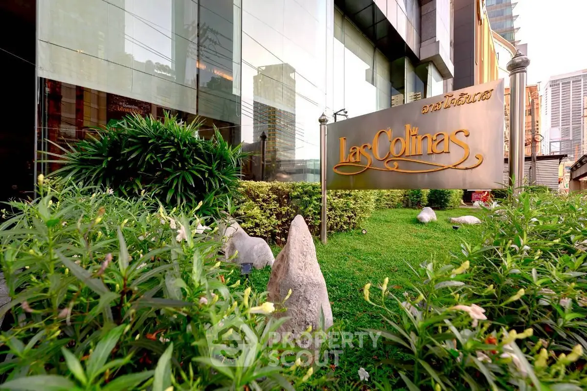 Luxurious Las Colinas building entrance with lush greenery and modern architecture.