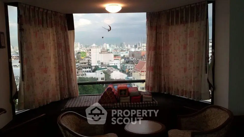 Cozy living room with panoramic city view through large window, featuring elegant seating and soft lighting.