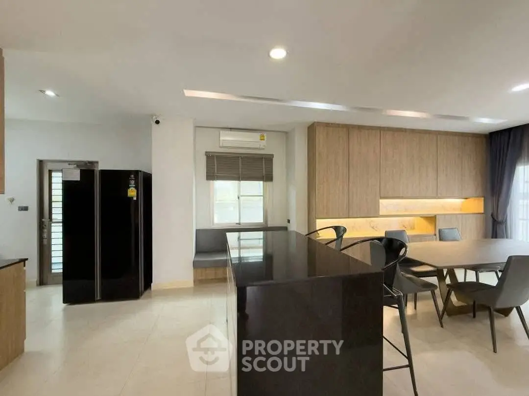 Modern kitchen with sleek design and dining area, featuring elegant cabinetry and ample natural light.