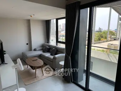 Modern living room with large windows and city view, featuring a cozy sectional sofa and stylish decor.