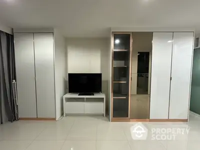 Modern living room with sleek white cabinets and a flat-screen TV on a glossy tiled floor.