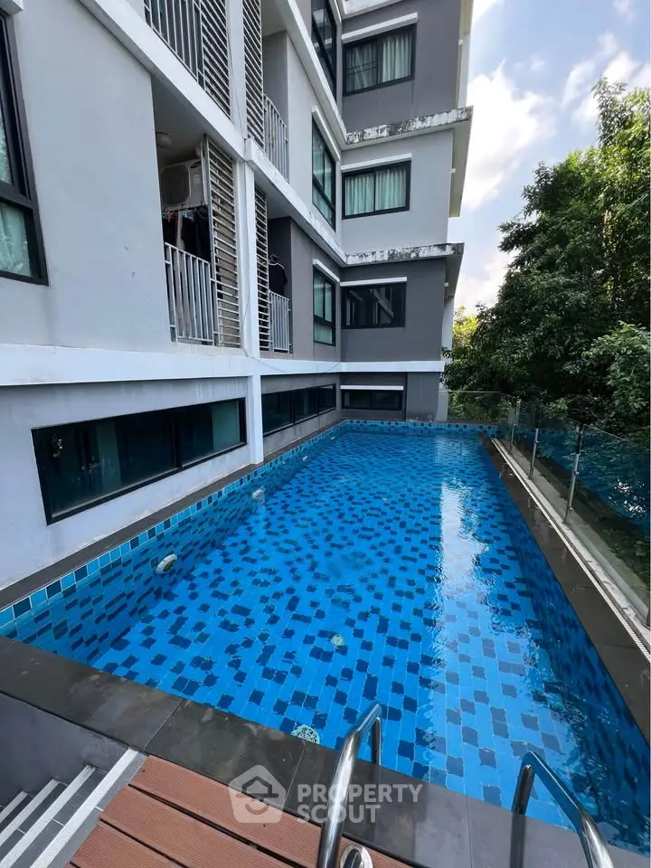 Modern apartment building with a sleek swimming pool and lush greenery.
