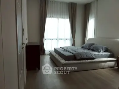 Modern bedroom with large window and stylish decor in a cozy apartment.