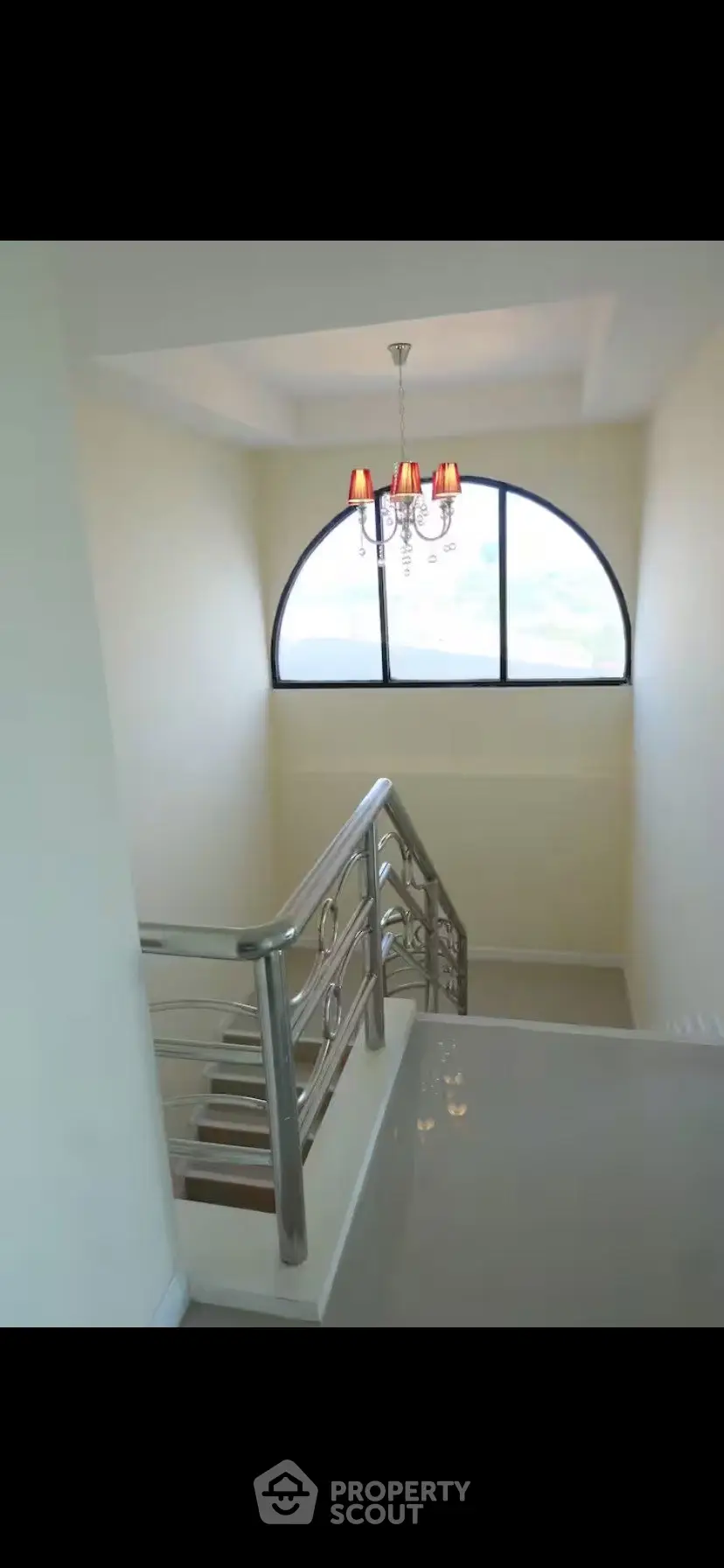 Elegant staircase with chandelier and large window in modern home