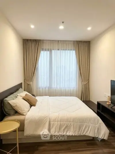 Cozy bedroom with large window and elegant curtains in modern apartment.