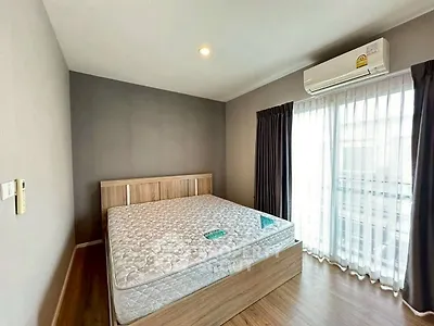 Modern bedroom with large window and air conditioning unit, featuring a stylish wooden bed frame.