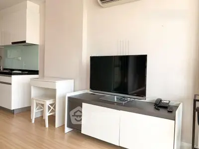 Modern living room with sleek TV setup and compact kitchen area