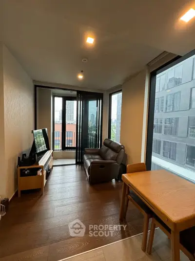 Modern living room with city view, featuring sleek furniture and large windows for natural light.