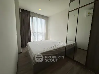 Modern bedroom with large window and mirrored wardrobe in a minimalist style.