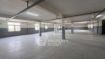 Spacious industrial-style open space with large windows and concrete flooring, ideal for versatile use.