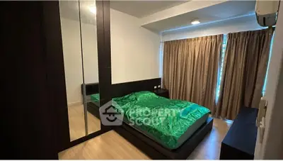 Modern bedroom with green bedding and mirrored wardrobe in stylish apartment.