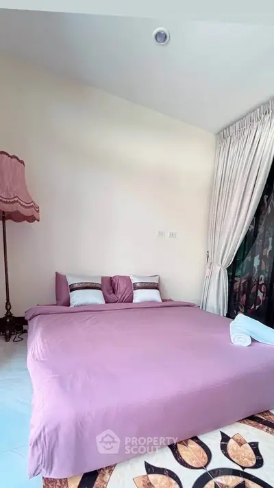 Cozy bedroom with pink bedding and elegant lamp, perfect for relaxation.