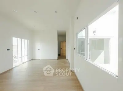 Spacious and bright empty room with large windows and wooden flooring