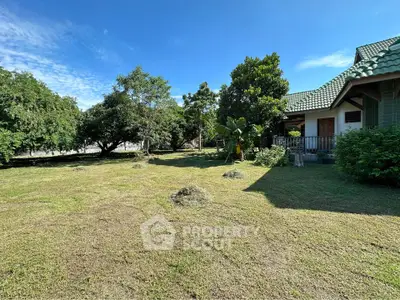 Spacious garden with lush greenery and charming house exterior under clear blue sky.