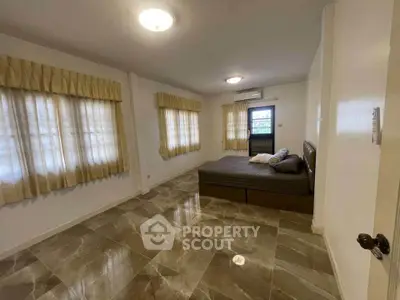 Spacious bedroom with elegant tile flooring and large windows for natural light.