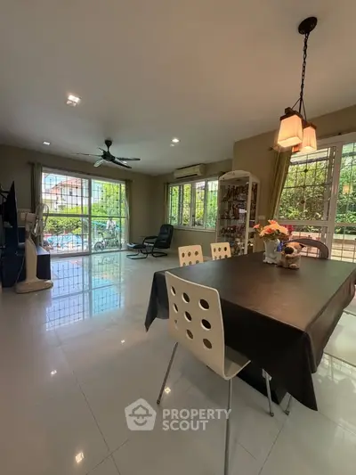 Spacious living room with dining area and large windows offering garden views.
