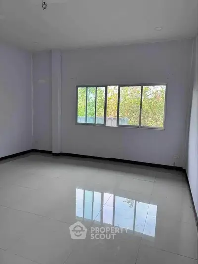 Spacious empty room with large window and glossy tiled floor