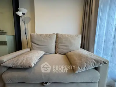 Cozy living room with plush beige sofa and elegant floor lamp by a large window.