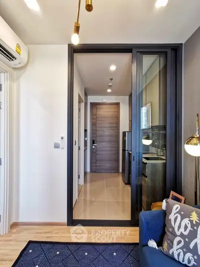 Modern apartment interior with stylish decor and sliding glass door leading to kitchen area.