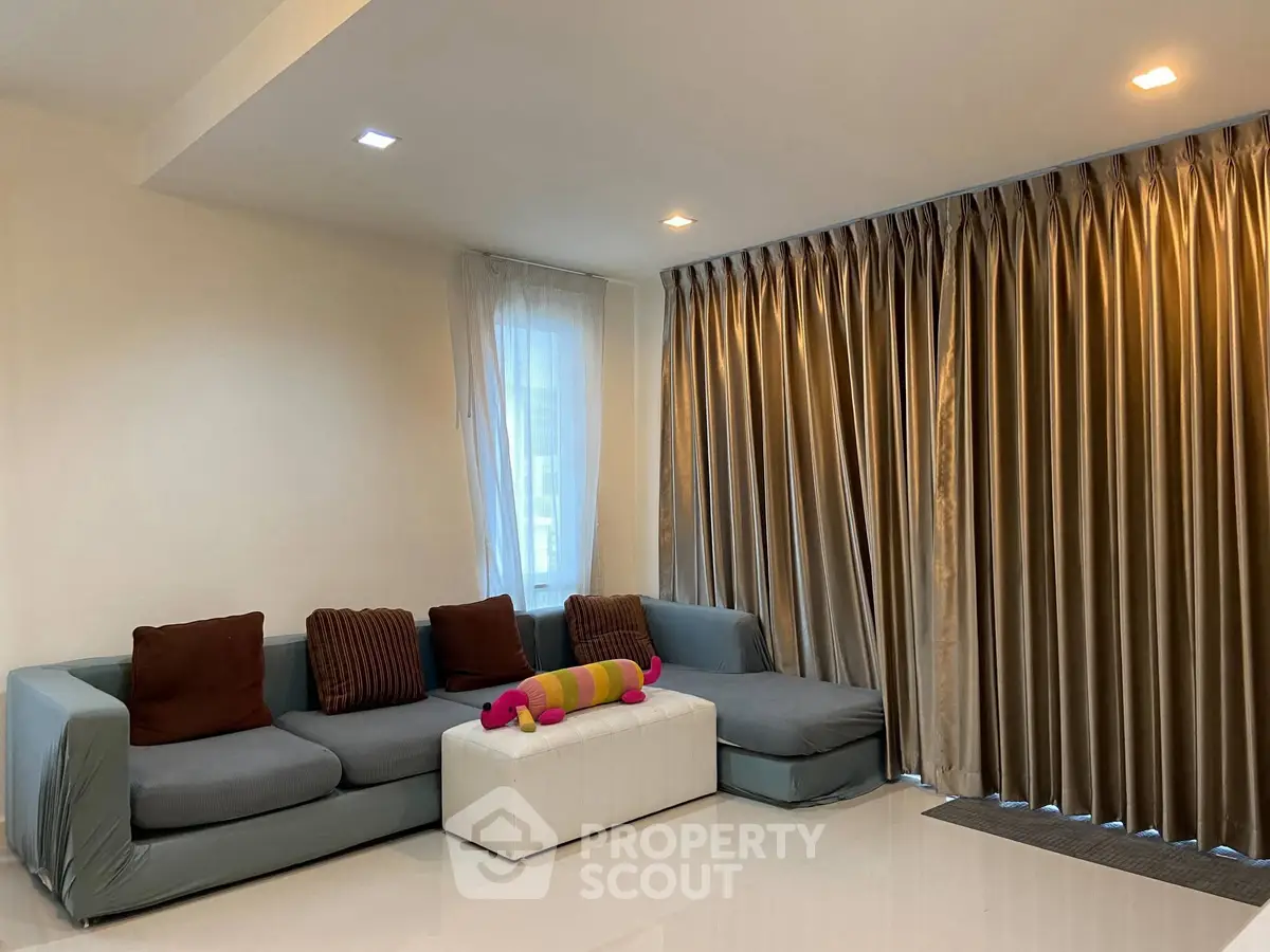 Spacious living room with modern sofa and elegant curtains, perfect for relaxation and entertaining guests.