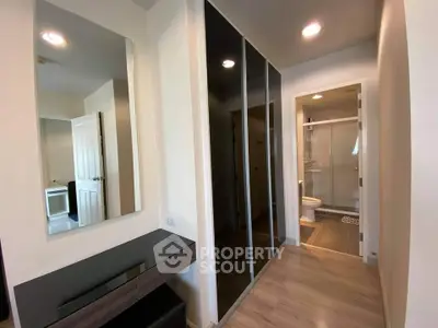 Modern apartment hallway with sleek mirrored closets and bathroom view