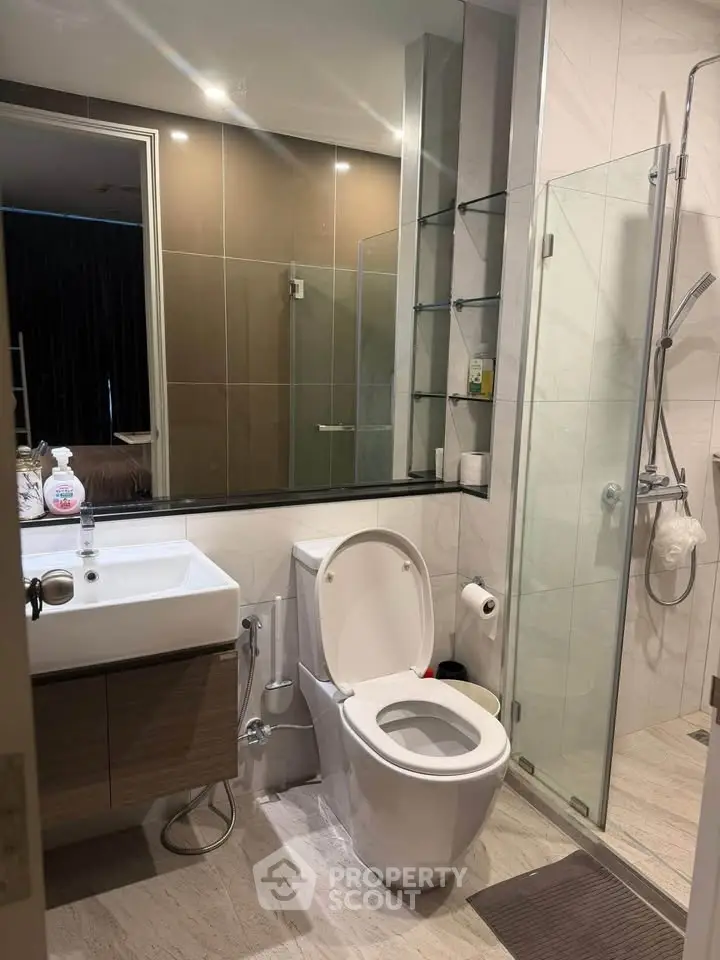Modern bathroom with glass shower, sleek vanity, and contemporary fixtures in a stylish apartment.