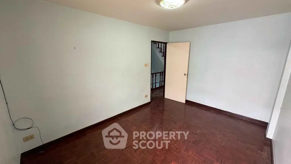 Spacious empty room with wooden flooring and white walls, ideal for customization.