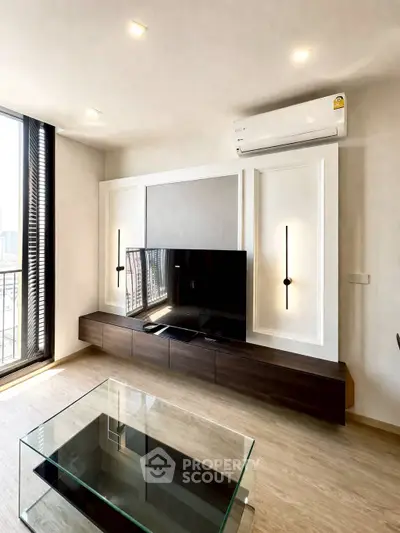 Modern living room with sleek design, featuring a glass coffee table and wall-mounted TV unit.