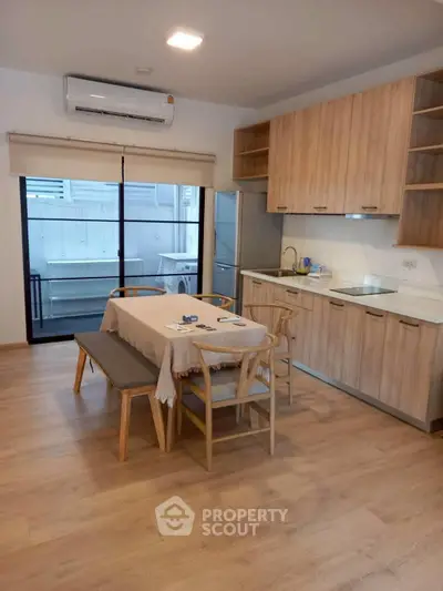 Modern kitchen with wooden cabinets and dining area in open layout apartment.