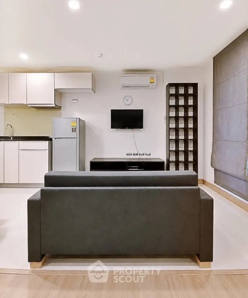 Modern living room with sleek furniture and open kitchen layout in a stylish apartment.