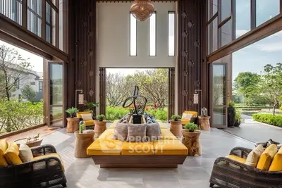 Luxurious open living room with high ceilings and garden view, featuring elegant decor and ample natural light.