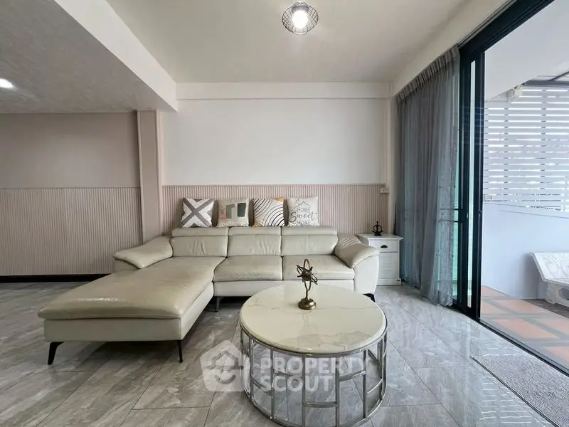 Spacious modern living room with elegant decor and large sliding glass doors to balcony.
